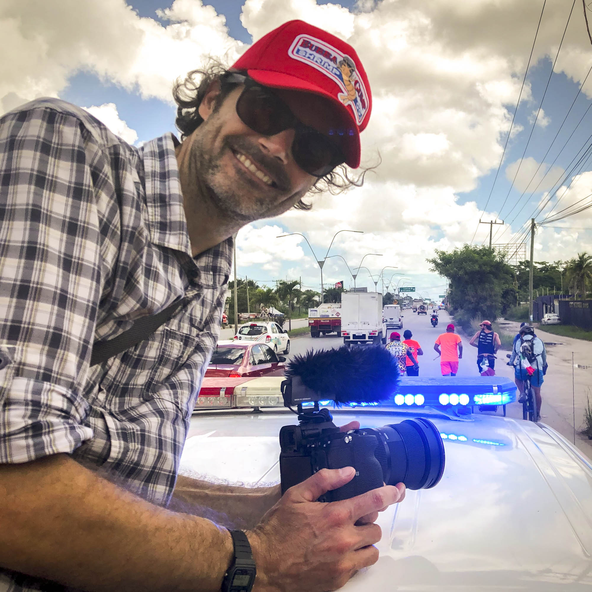 Daniel Rintz working on a documentary in Mexico, riding on the back of a police car.